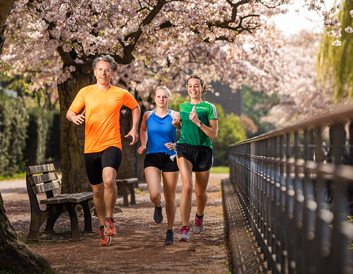 3 Personen beim Laufen durch eine Kirschblüten Allee