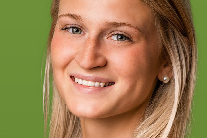 Bild einer lächelnden Frau. Einfarbiger, grüner Hintergrund.