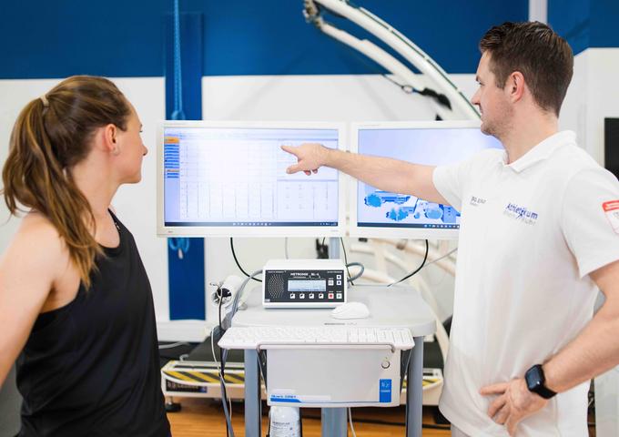 Der Arzt erklärt der Patientin ihre Gesundheitswerte vor zwei Monitoren