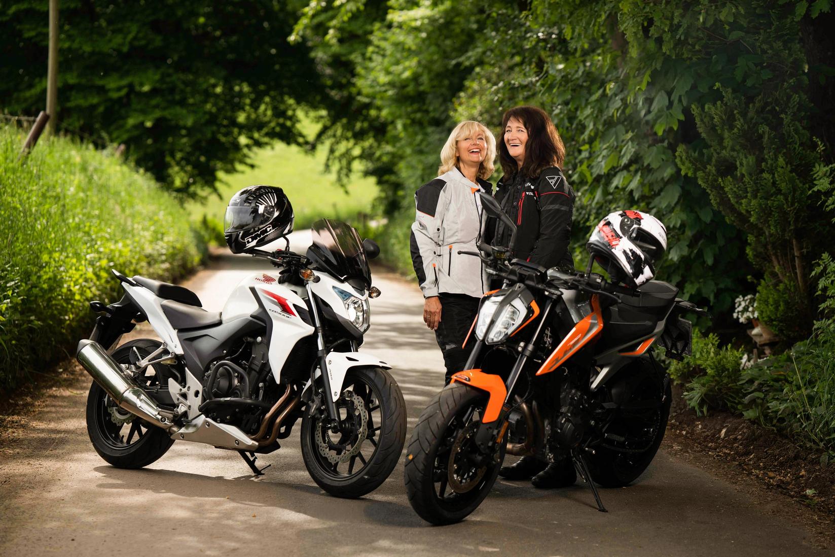 Zwei gutgelaunte Frauen mit Motorrädern