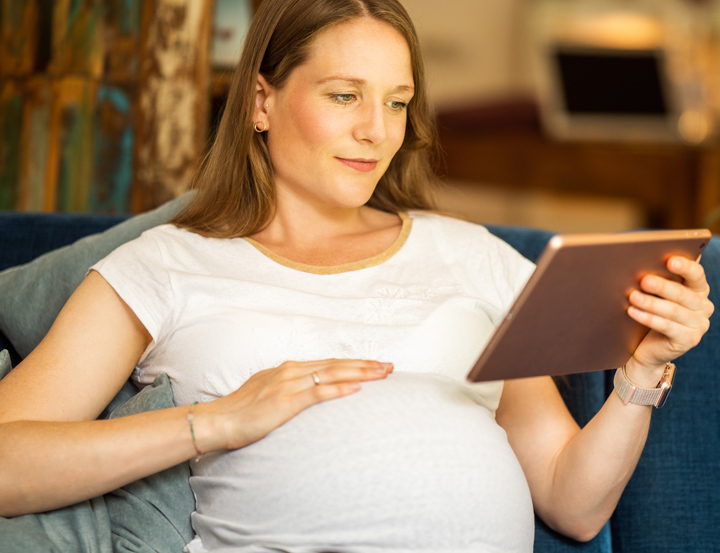 Schwangere Frau hält ein Tablet