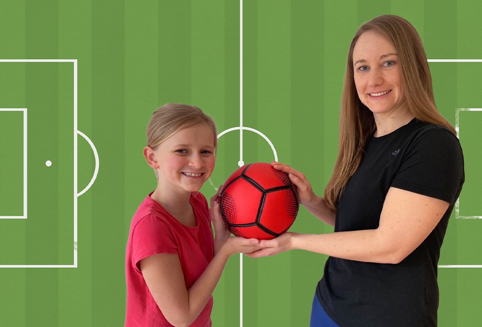 Junge Frau und Mädchen halten zusammen einen Fußball feste.